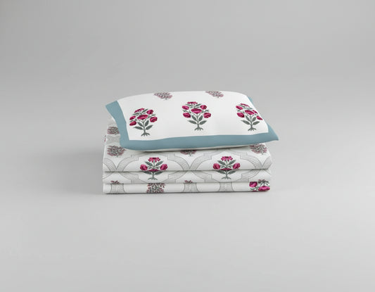 Floral patterned bedspread on a bed with matching pillows, surrounded by nightstands and decor.