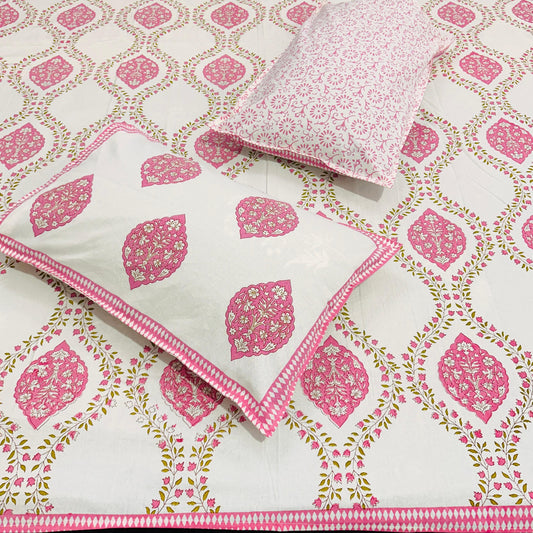 Pink and white patterned bedsheet with pillows on a matching background
