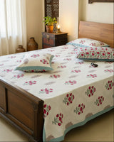 Rose pink floral booti cotton bedsheet with a blue border on a carved wooden bed