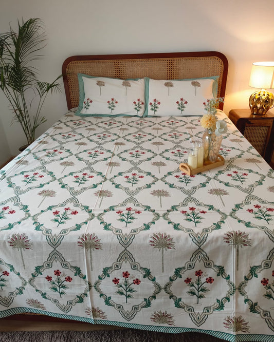 Bed with floral patterned bedsheet and matching pillows in a bedroom setting.