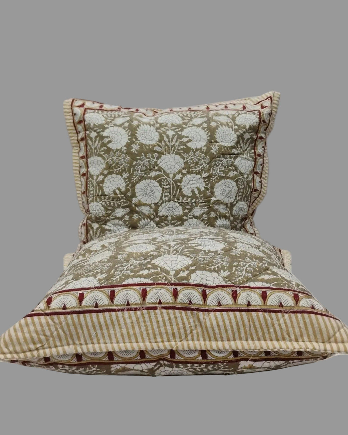 Two Kumud beige quilted cushion covers stacked to show the floral print and striped reverse