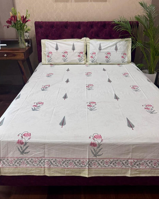 Bed with floral bedspread and pillows in a bedroom setting