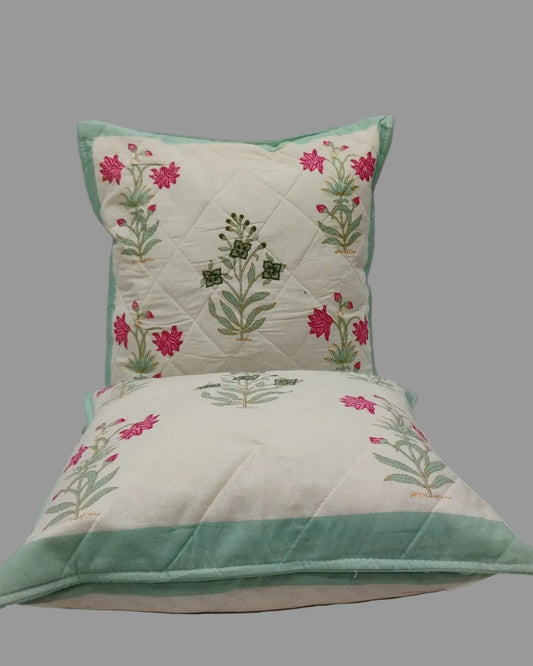 Two Malika blue quilted cushion covers stacked to show the floral print and mint trim