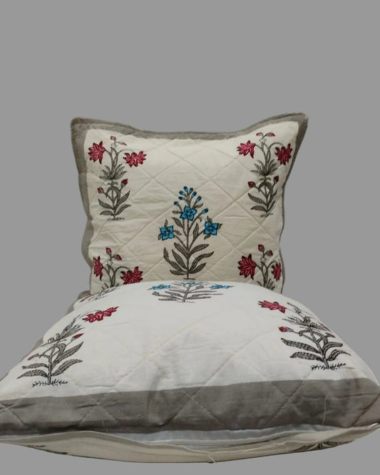 Two Malika grey quilted cushion covers stacked to show the floral print and grey trim