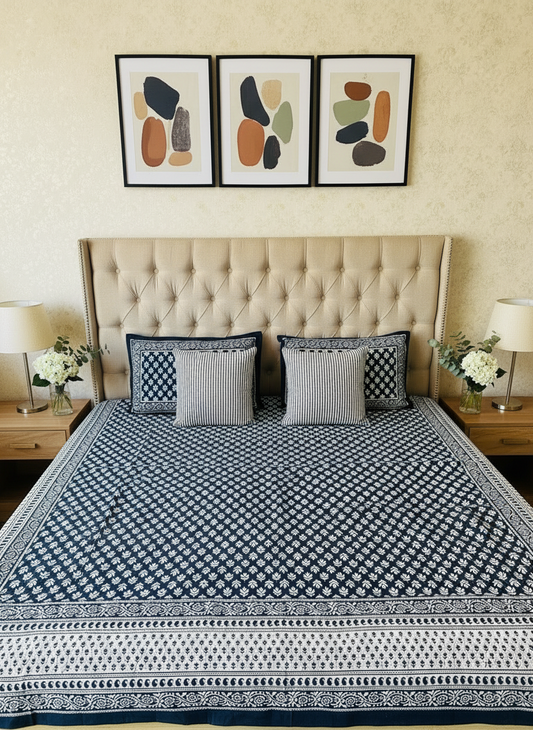 Bed with blue and white patterned bedspread and pillows against a beige wall.