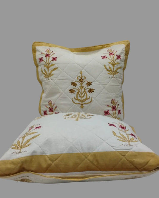 Two Mehek yellow quilted cushion covers stacked to show the floral print and ochre trim