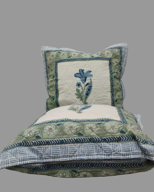 Two Mridula blue quilted cushion covers stacked to show the floral borders and striped reverse