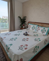 Nargis Green Everyday Cotton bedsheet – coral and teal botanical florals on a cane headboard bed