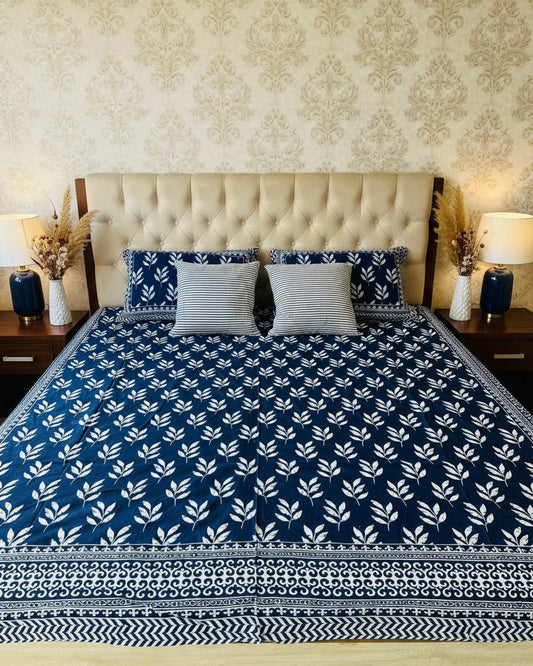 Bed with blue and white patterned bedspread and matching pillows.