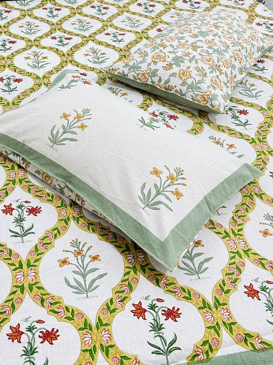 Bed with floral patterned bedsheet and 2 reversible pillow in green yellow and red