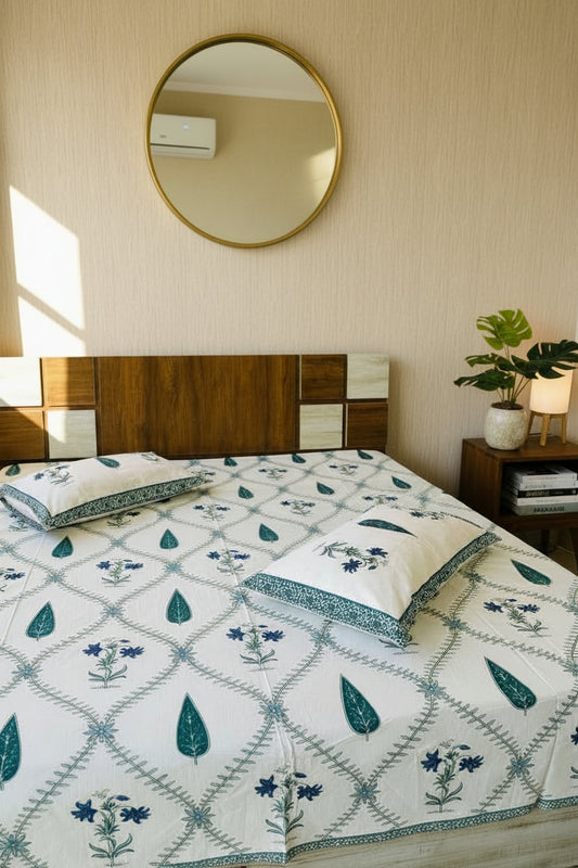 Bed with floral patterned bedspread and pillows in a room.