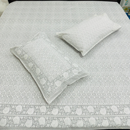 Gray patterned bedspread with matching pillows on a bed