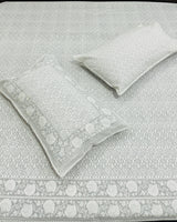 Gray patterned bedspread with matching pillows on a bed