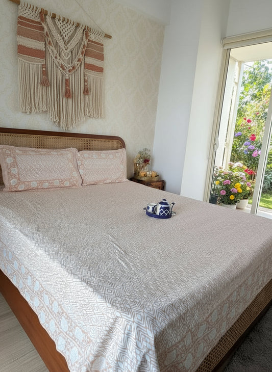 Bedroom with a bed featuring a patterned bedsheet and pillows in peach and white, a nightstand with a lamp