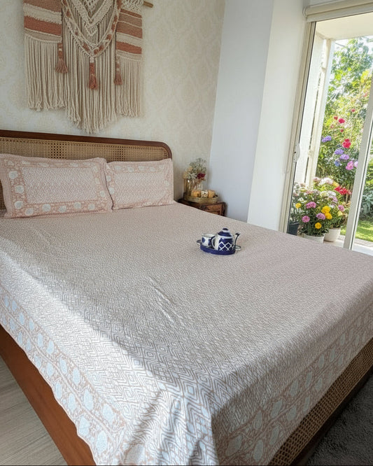 Bedroom with a bed featuring a patterned bedsheet and pillows in peach and white, a nightstand with a lamp
