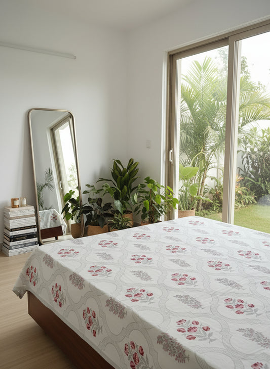 Bedroom with floral bedspread, plants, and a large mirror.