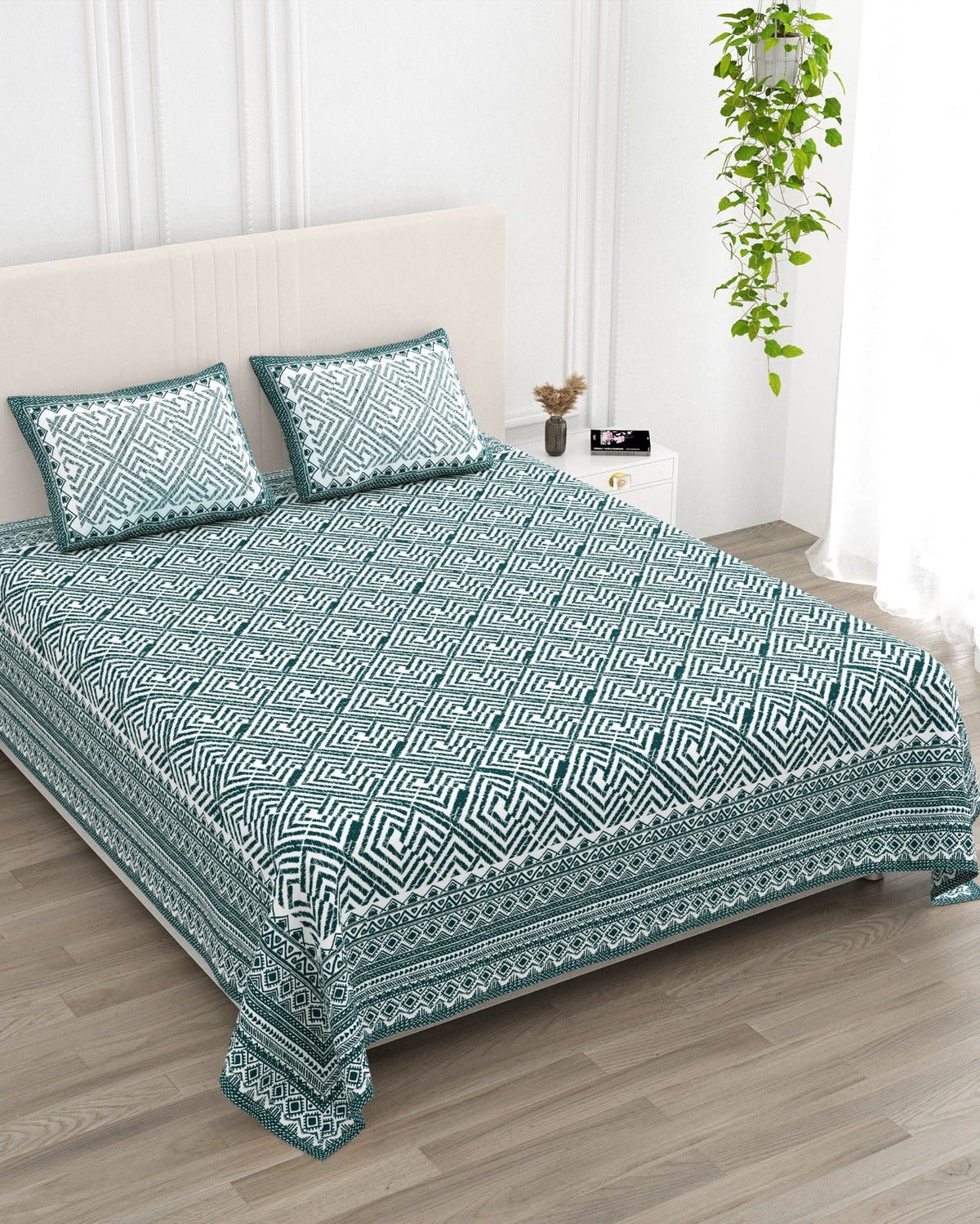 Aakriti Blue bedsheet, deep teal diamond-maze print, in a studio shot against a cream headboard