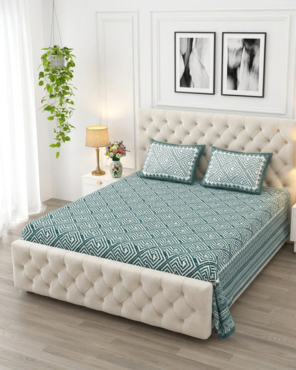 Aakriti Blue bedsheet, deep teal diamond-maze print, on a tufted ivory bed
