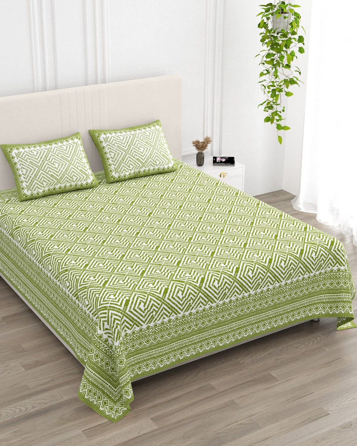 Aakriti Green bedsheet, leaf-green diamond-maze print, in a studio shot against a cream headboard