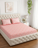 Aakriti Pink bedsheet, coral-pink diamond-maze print, on a tufted ivory bed
