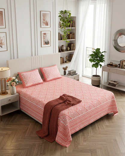 Aakriti Pink bedsheet, coral-pink diamond-maze print, in a bedroom with a maroon knit throw