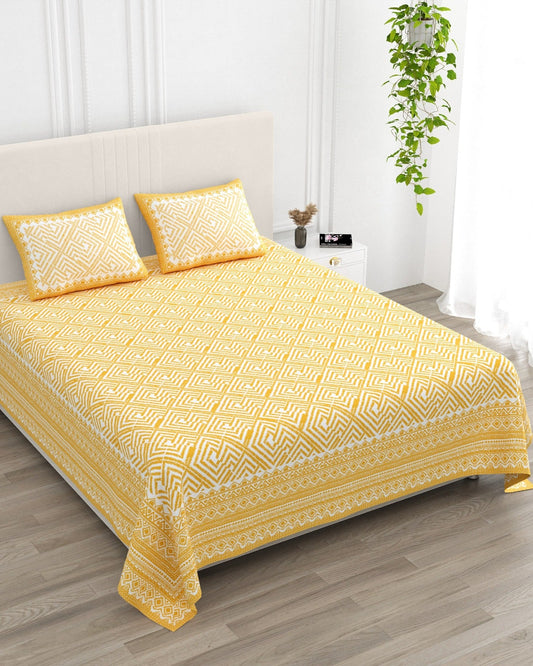 Aakriti Yellow bedsheet, marigold-yellow diamond-maze print, in a studio shot against a cream headboard