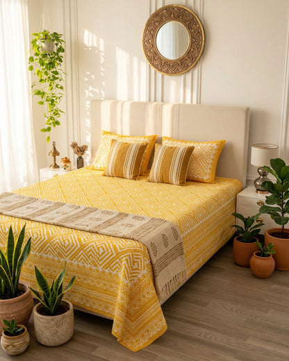 Aakriti Yellow bedsheet, marigold-yellow diamond-maze print, on a bed with a cream headboard with striped cushions and a runner