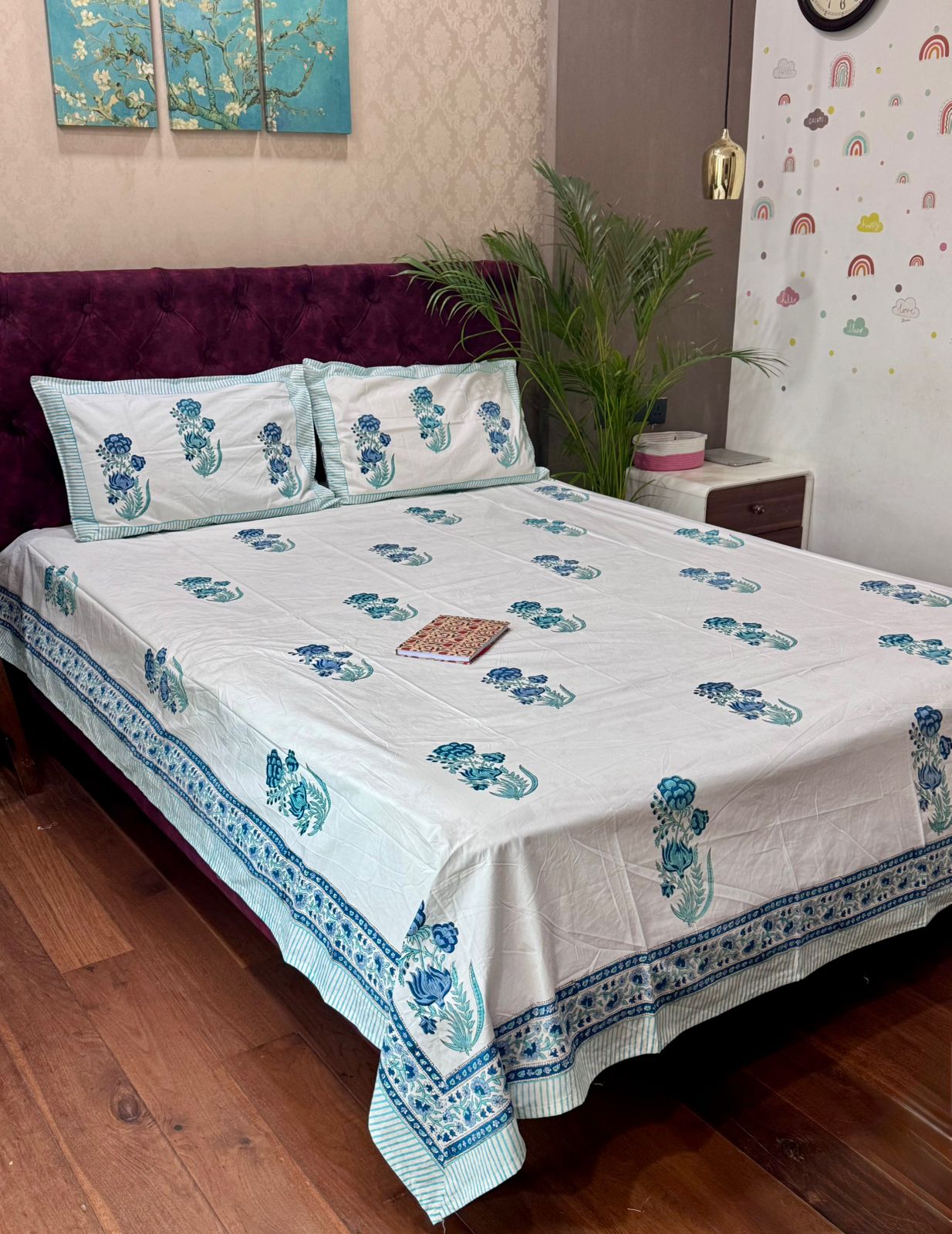 Bed with floral bedspread and pillows in a room with decor elements.