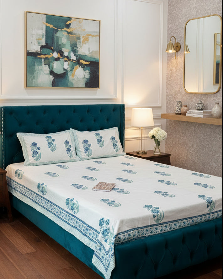 Bed with floral bedspread and pillows in a room with decor elements.