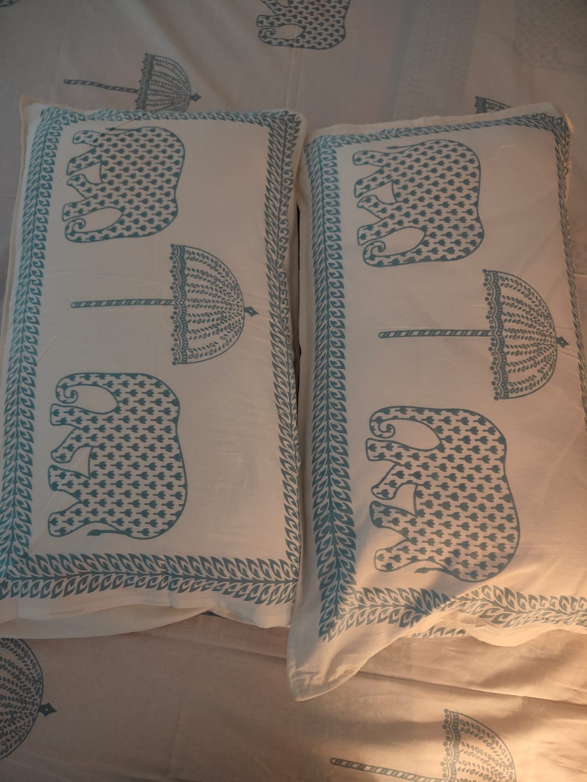 Two white pillows with blue elephant patterns on a matching bedsheet background.
