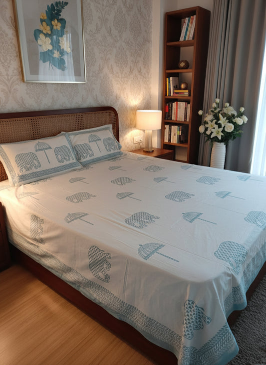 Bedroom with a bed featuring elephant-patterned bedding, a tray with candles and flowers on a wooden nightstand.