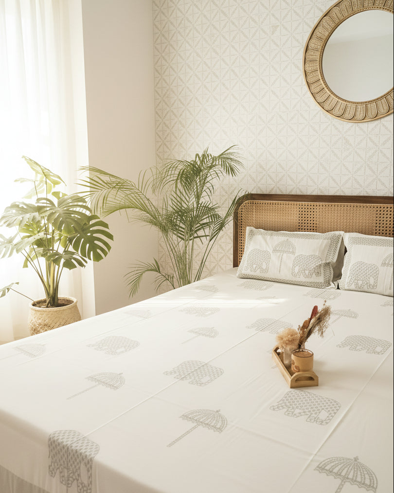 Bedroom with a bed featuring elephant-patterned bedding, a nightstand, and decorative items.