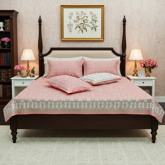 Pink floral patterned bedspread with matching pillows on a bed.