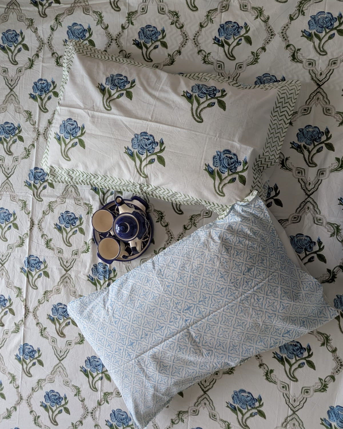Decorative pillow and bedsheet on a blue floral-pattern