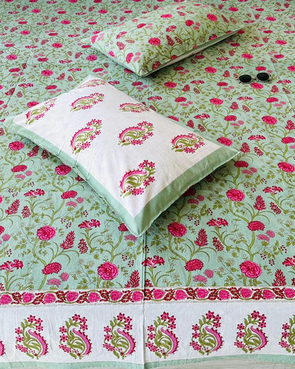 Close-up of sage green cotton fabric with pink roses and a paisley print pillow cover