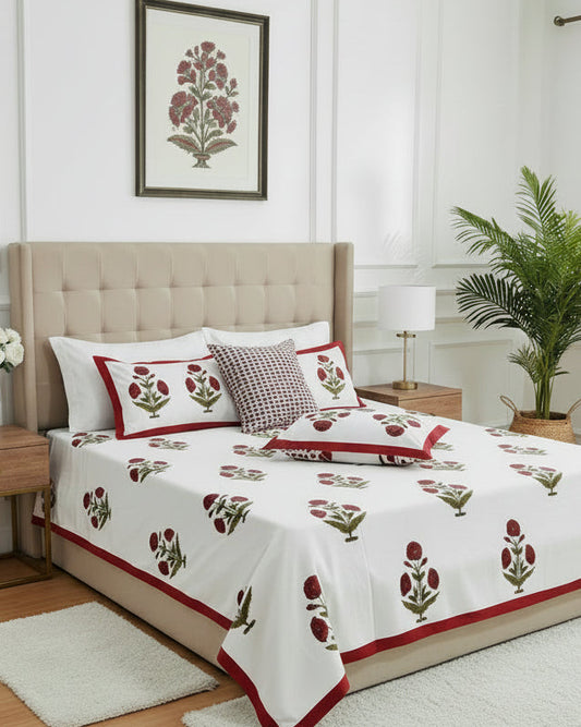 Bedroom with floral bedspread, pillows, and a plant.