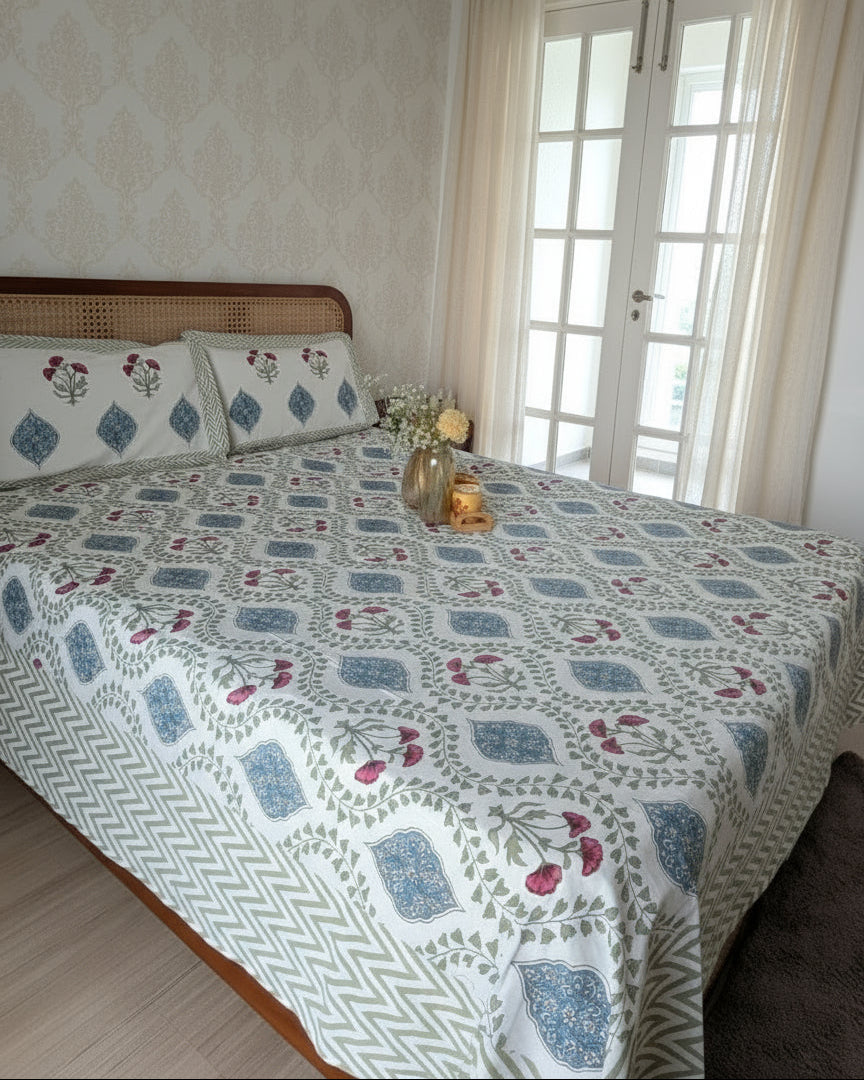 Bed with floral patterned bedsheet in a room with light-colored walls and a window.