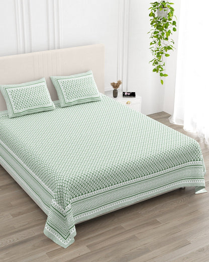 Booti Green bedsheet, sage-green lattice with tiny white booti, in a studio shot against a cream headboard