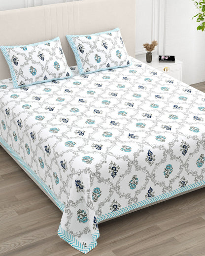 Chameli Blue bedsheet, grey trellis jaal on white with aqua bloom booti, in a studio shot against a cream headboard