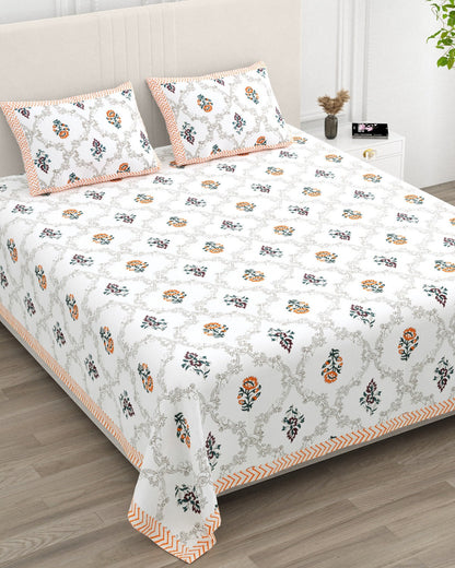 Chameli Orange bedsheet, grey trellis jaal on white with orange bloom booti, in a studio shot against a cream headboard