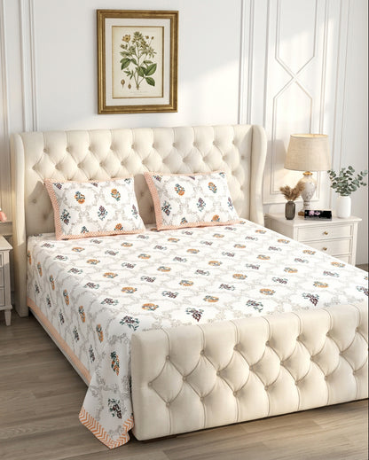 Chameli Orange bedsheet, grey trellis jaal on white with orange bloom booti, on a tufted wingback bed