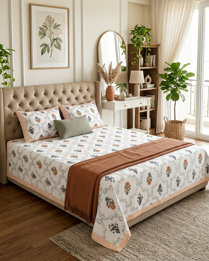 Chameli Orange bedsheet, grey trellis jaal on white with orange bloom booti, on a bed with a tufted headboard with a rust throw