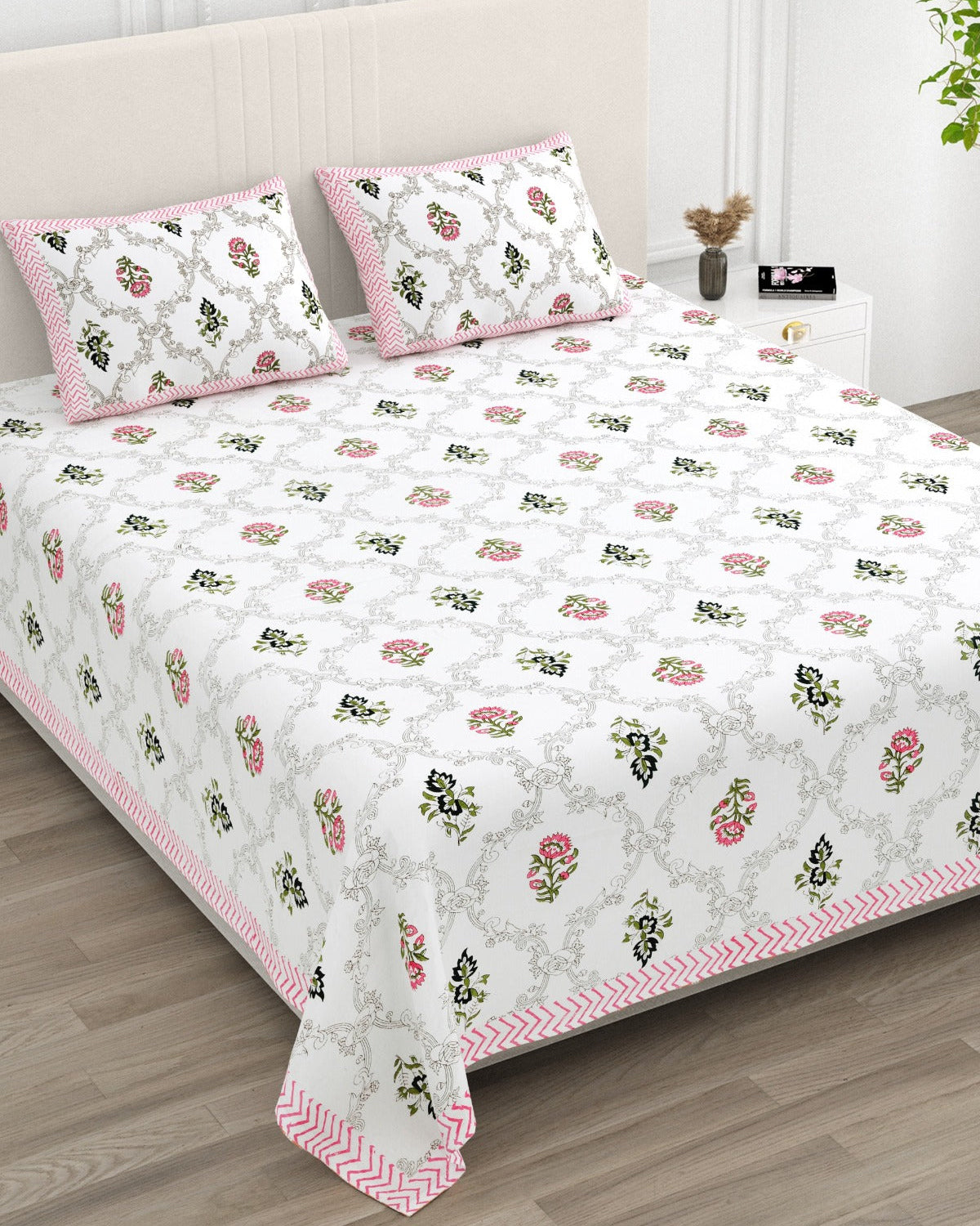Chameli Pink bedsheet, grey trellis jaal on white with pink bloom booti, in a studio shot against a cream headboard