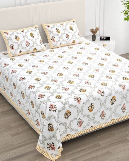 Chameli Yellow bedsheet, grey trellis jaal on white with mustard roundel bloom booti, in a studio shot against a cream headboard