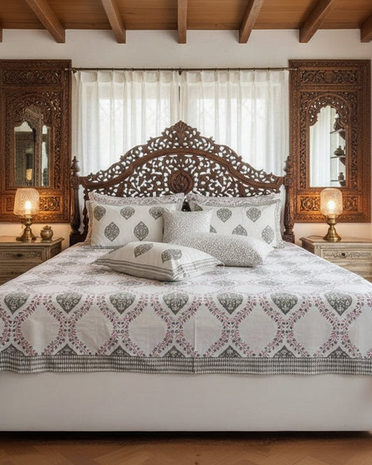 Patterned bedsheet with geometric and leaf designs on a bedspread.