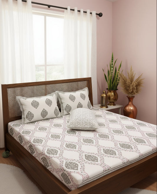 Patterned bedsheet with geometric and leaf designs on a bedspread.