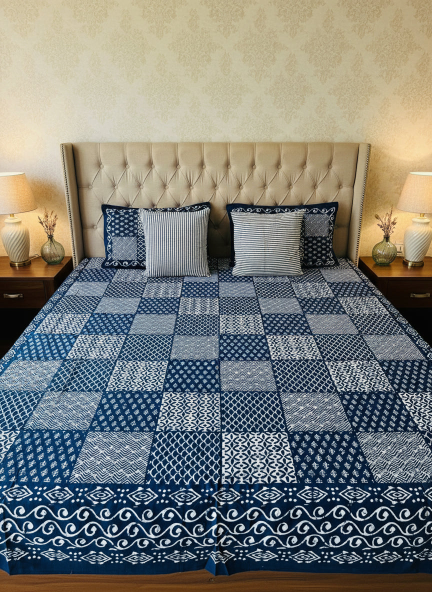 Blue and white patterned bedspread on a bed with matching pillows.