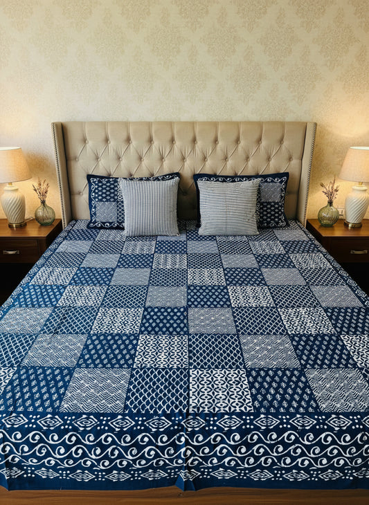 Blue and white patterned bedspread on a bed with matching pillows.