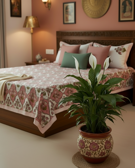 Decorative bedroom with a bed, pillows, and a potted plant on a side table.