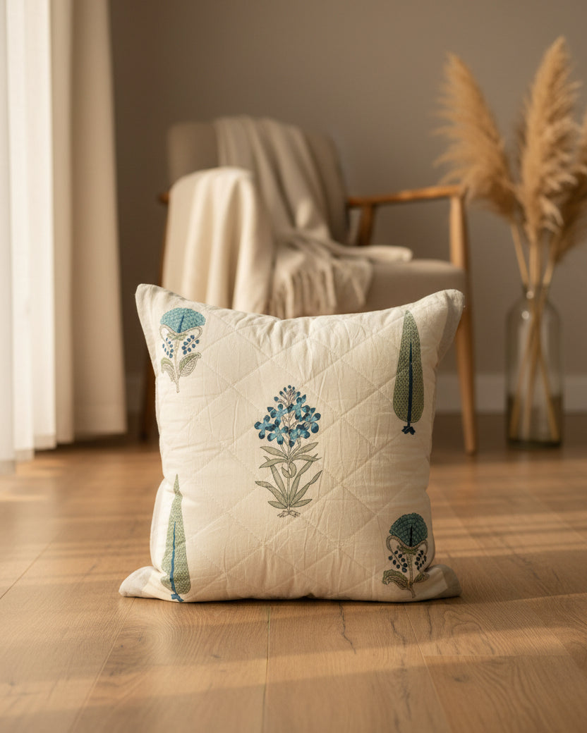 Gulmohar grey quilted cushion cover styled with blue floral and tree motifs